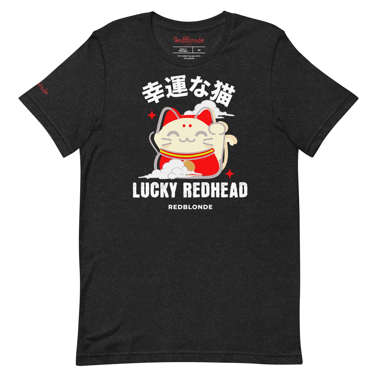 A black heather unisex T-shirt featuring a colorful maneki-neko (lucky cat) graphic wearing a red outfit with gold accents. Above the cat, Japanese kanji characters are printed in bold white. Below the illustration, the text reads “LUCKY REDHEAD” in distressed white font, with “REDBLONDE” in smaller uppercase letters underneath. The shirt has short sleeves, a classic crew neckline, and a casual, modern fit.