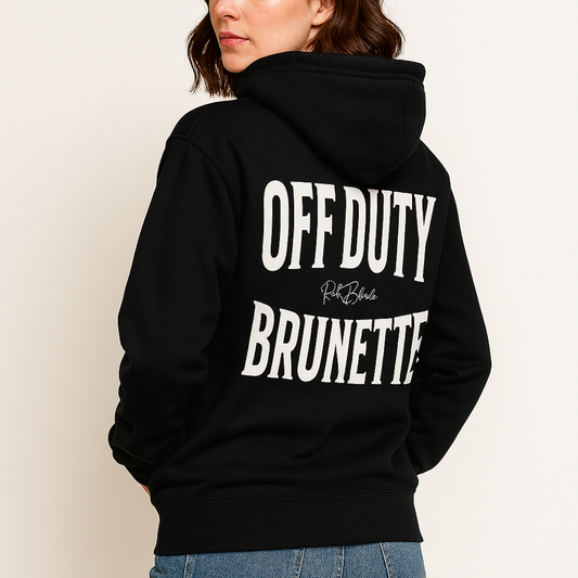 A brunette wears a classic black unisex hoodie with the words 'OFF DUTY BRUNETTE' written in large Brookfield white font, across the back. Branded RedBlonde London in red on inside neck and right sleeve