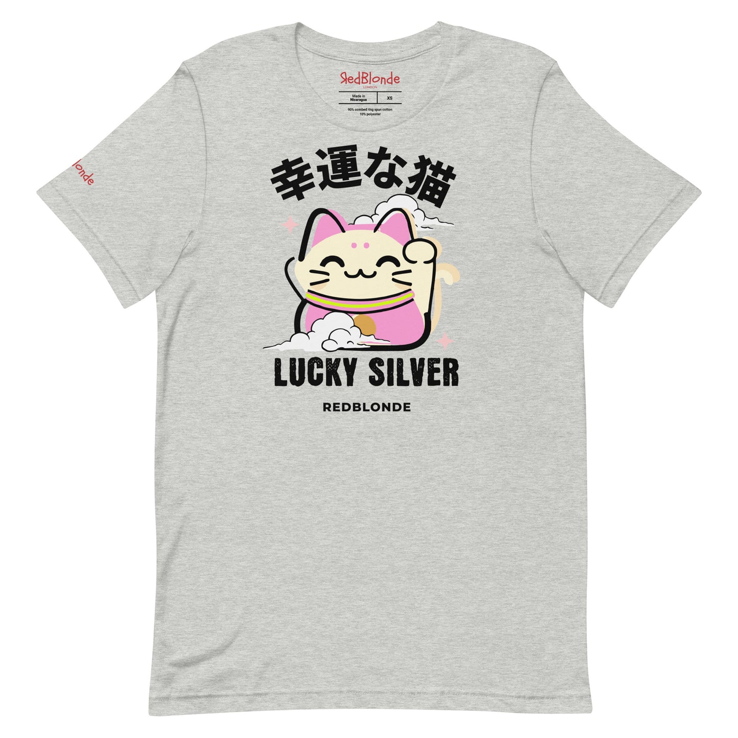 A grey unisex T-shirt featuring a colourful illustration of a lucky cat (Maneki-neko) with pink ears and accents, smiling and waving one paw. Above the cat are Japanese characters reading "幸運な猫" (Lucky Cat), and below it are the words "LUCKY SILVER" in bold black font, followed by "REDBLONDE" in smaller text. The design is playful and cute, with stars and a cloud adding charm. The RedBlonde brand name appears in red on the inside label and on the right sleeve.