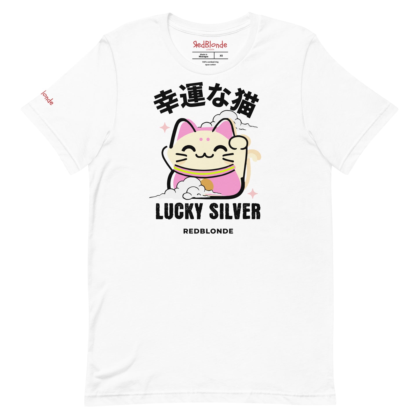 A white unisex T-shirt featuring a colourful illustration of a lucky cat (Maneki-neko) with pink ears and accents, smiling and waving one paw. Above the cat are Japanese characters reading "幸運な猫" (Lucky Cat), and below it are the words "LUCKY SILVER" in bold black font, followed by "REDBLONDE" in smaller text. The design is playful and cute, with stars and a cloud adding charm. The RedBlonde brand name appears in red on the inside label and on the right sleeve.
