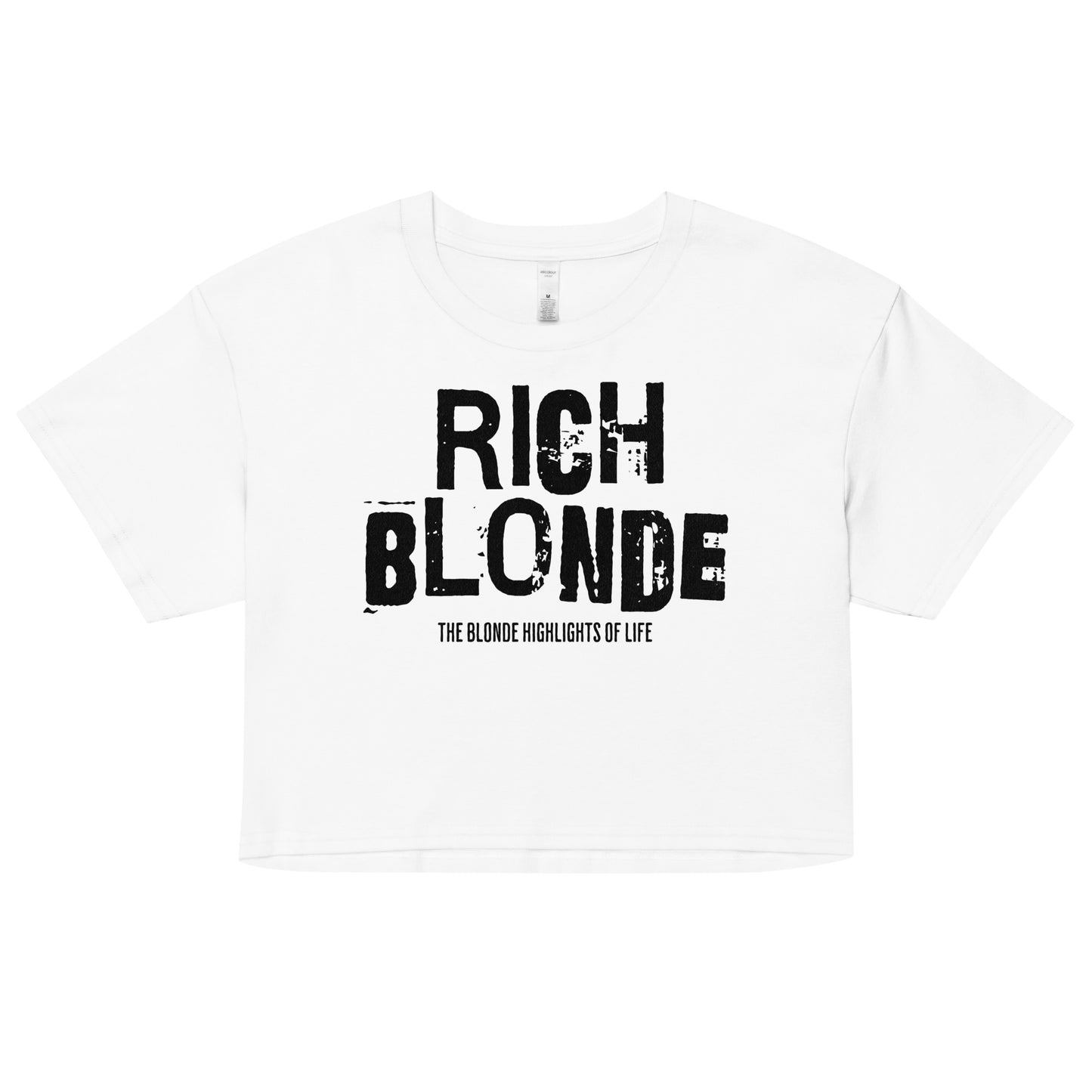 A white women’s crop top with a relaxed fit, short sleeves, and a wide crew neckline. The front features bold black distressed lettering reading “RICH BLONDE” with the tagline “THE BLONDE HIGHLIGHTS OF LIFE” in smaller text below.