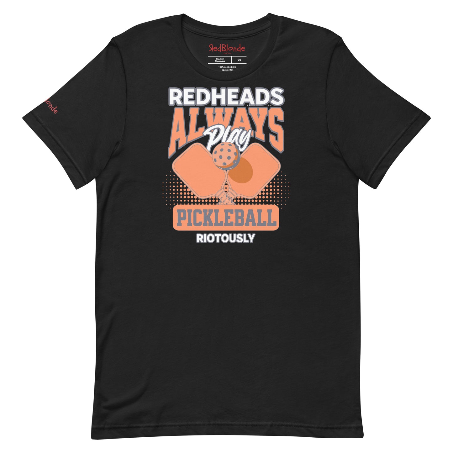 Black unisex t-shirt with orange graphic that reads "Redheads Always Play Pickleball Riotously," featuring pickleball paddles and ball. Branded RedBlonde on inside neck and right sleeve