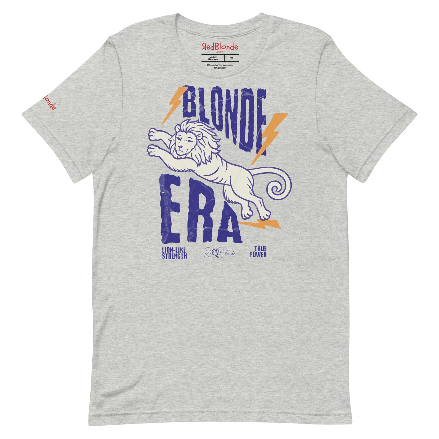 Grey unisex short-sleeve t-shirt featuring a bold graphic of a leaping lion outlined in purple, surrounded by orange lightning bolts. The text “BLONDE ERA” appears in large distressed purple letters, with smaller text reading “LION-LIKE STRENGTH” and “TRUE POWER” underneath. Signed RedBlonde. The brand name “RedBlonde” is printed in red on the inside collar label and on the right sleeve near the cuff.