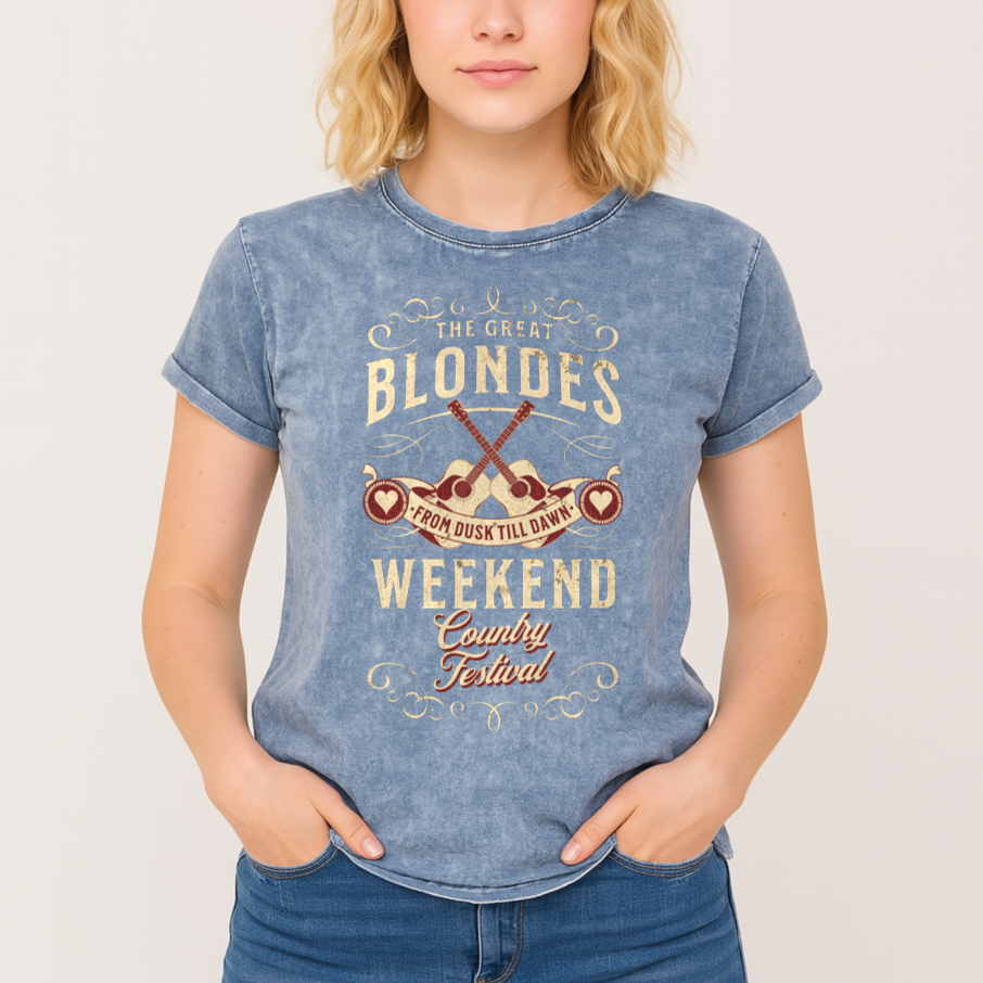 Blonde wears a unisex t-shirt in blue denim wash with a graphic featuring ‘THE GREAT BLONDES WEEKEND’ in Brookfield font and ‘Country Festival’ in Milkstore font around two guitars and a banner saying ‘From Dust Till Dawn’. Branded RedBlonde London on inside neck and right sleeve