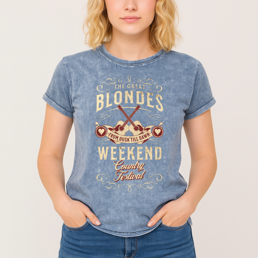 Blonde wears a unisex t-shirt in blue denim wash with a graphic featuring ‘THE GREAT BLONDES WEEKEND’ in Brookfield font and ‘Country Festival’ in Milkstore font around two guitars and a banner saying ‘From Dust Till Dawn’. Branded RedBlonde London on inside neck and right sleeve
