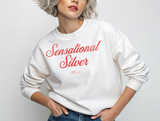 Blonde wears classic white relaxed fit unisex sweatshirt with the words 'Sensational Silver' written in red vintage milkstore font, like coco cola script. Branded RedBlonde London in red on inside neck and right sleeve