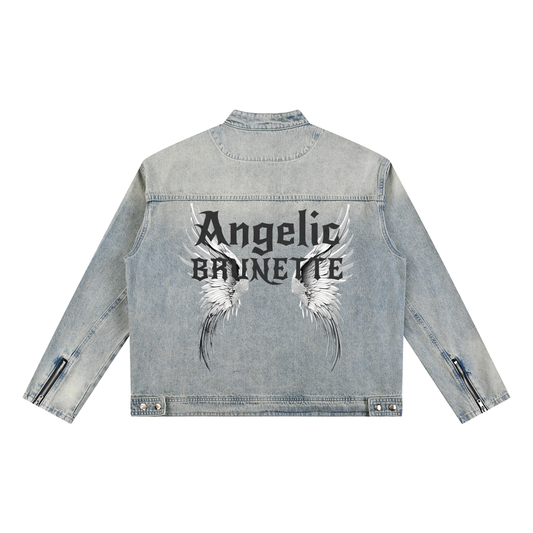 A light-wash denim jacket shown from the back on a white background. The sleeves have zippered cuffs, and the back features a large graphic with white angel wings and black gothic New Rocker style text reading “Angelic BRUNETTE.”