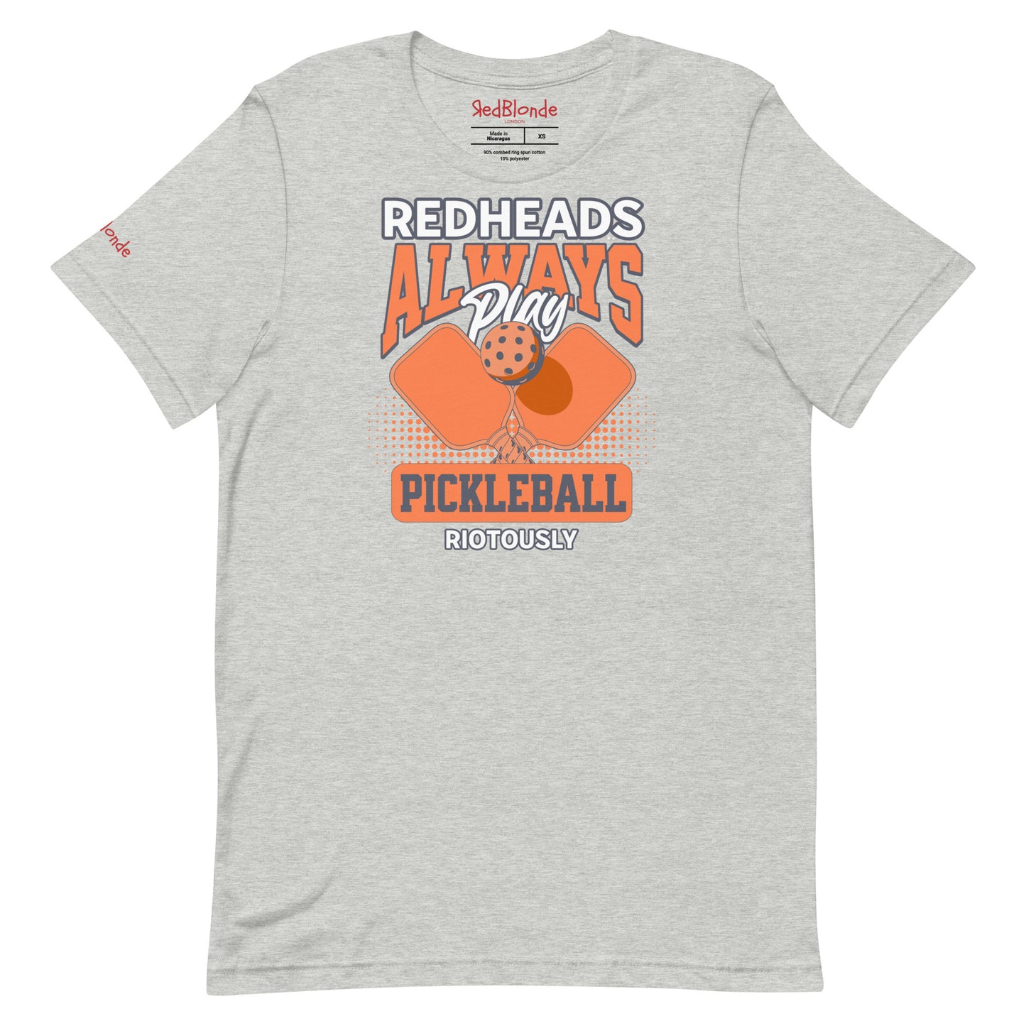 Grey unisex t-shirt with orange graphic that reads "Redheads Always Play Pickleball Riotously," featuring pickleball paddles and ball. Branded RedBlonde on inside neck and right sleeve
