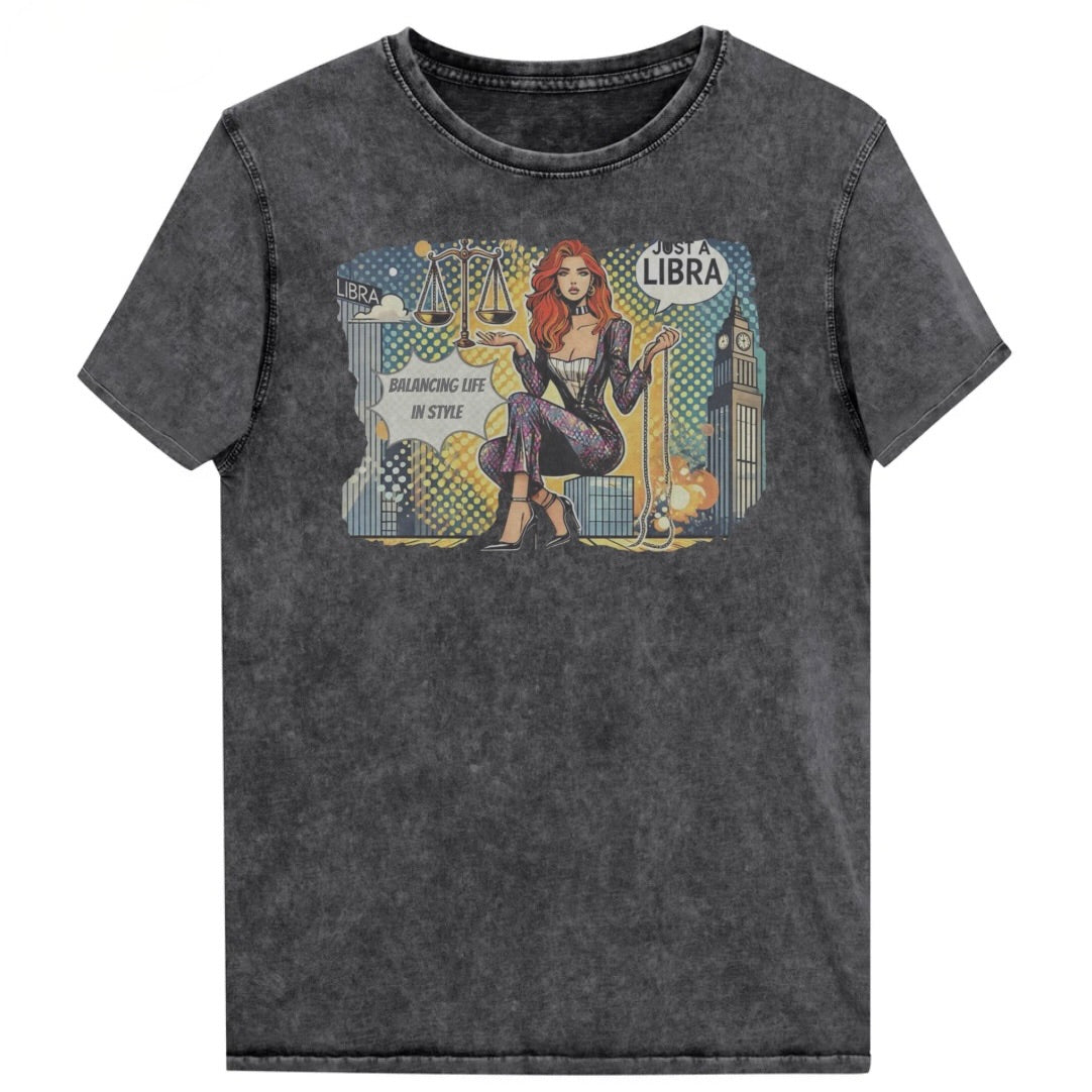 Flatlay of a unisex black denim wash vintage t-shirt with a retro pop-art redhead Libra graphic featuring a redhead woman, scales, and a city backdrop, captioned ‘Just a Libra, Balancing Life in Style’. Branded RedBlonde on inside neck and right sleeve