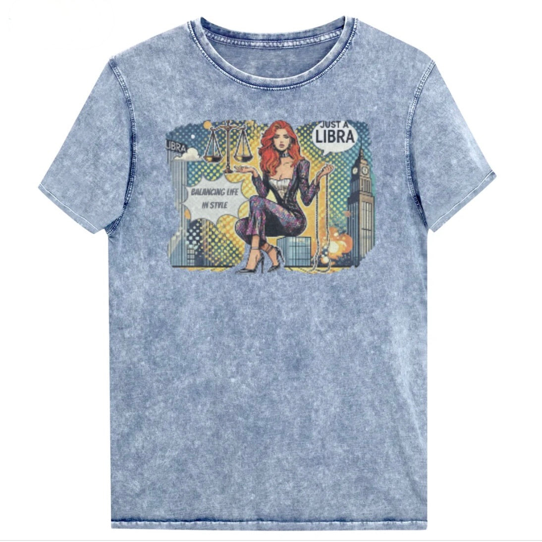 Flatlay of a unisex blue denim wash vintage t-shirt with a retro pop-art redhead Libra graphic featuring a redhead woman, scales, and a city backdrop, captioned ‘Just a Libra, Balancing Life in Style’. Branded RedBlonde on inside neck and right sleeve