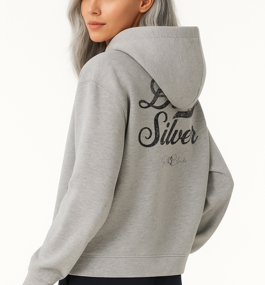 Back view of Model wearing a grey hoodie with bold black Milkstore vintage-style script text “Dirty Silver” across the back and a subtle RedBlonde signature logo underneath.
