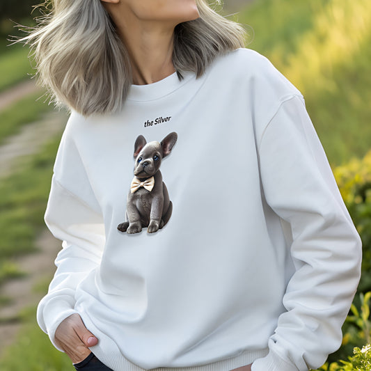 Model with silver grey hair wearing white relaxed fit unisex sweatshirt with a cute graphic of a silver grey puppy wearing a bow-tie and the words 'the Silver' linking to gray hair. Branded RedBlonde in red on inside neck and right cuff
