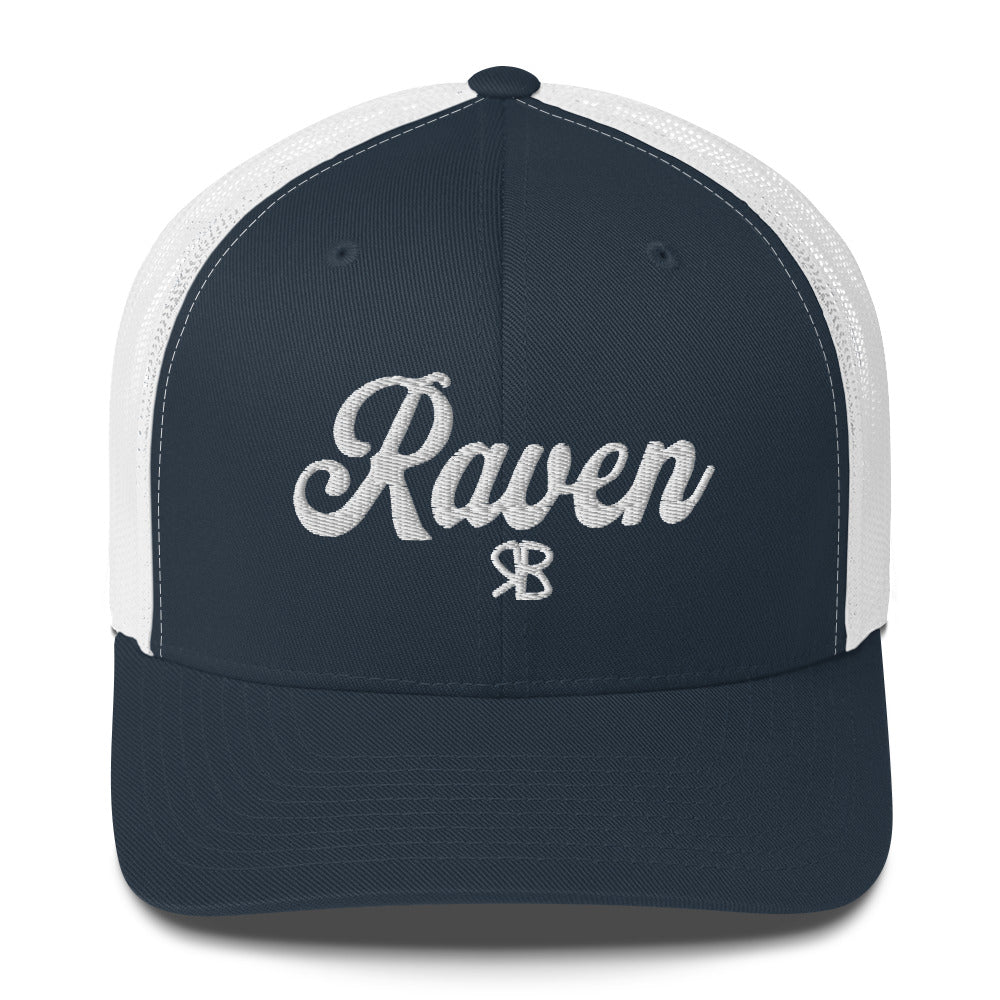 Navy/white trucker cap with 'Raven' in white adventurer 01 font on front. Branded RB