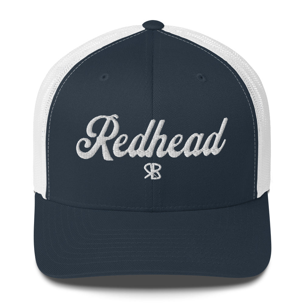 Navy /white trucker cap with 'Redhead' in white adventurer 01 font on front. Mesh back. Branded RB