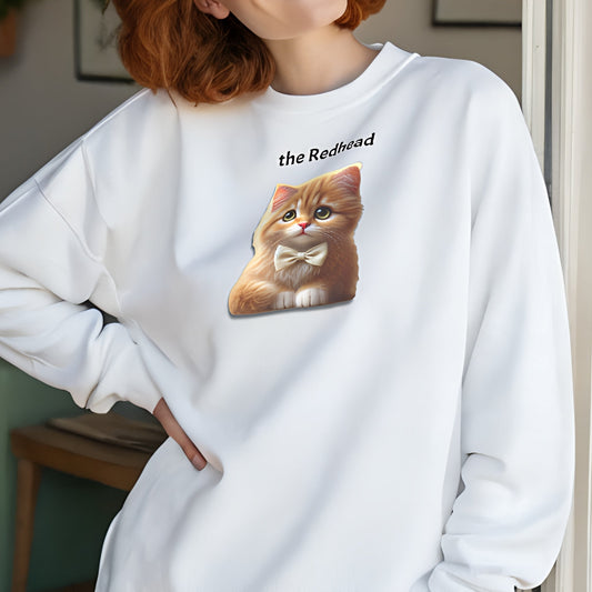 Redhead model wears white relaxed fit unisex sweatshirt with a cute graphic of a redhead kitten wearing a bow-tie and the words 'the Redhead' linking to Red hair. Branded RedBlonde in red on inside neck and right cuff