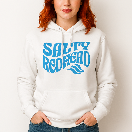 Redhead wears a classic relaxed fit unisex hoodie in white 'Salty Redhead' play on words slogan in blue retro 70s wavy text. Branded RedBlonde in red in inside neck and right cuff