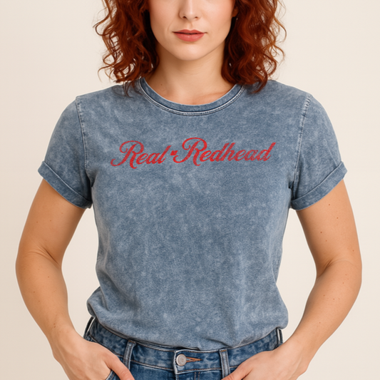 Redhead wears a unisex relaxed fit vintage blue denim wash slogan t-shirt with 'Real Redhead' in milkshake script red font. Branded RedBlonde in red on inside neck and right sleeve