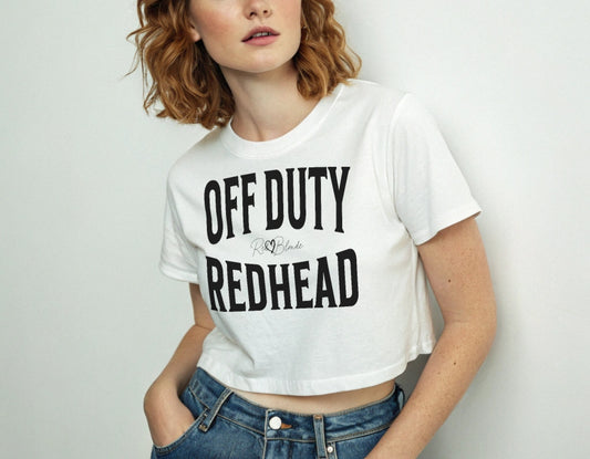 Redhead wears a white women's crop top graphic t-shirt with “OFF DUTY REDHEAD” in black Helvetica Now font emblazoned on the front, signed off RedBlonde