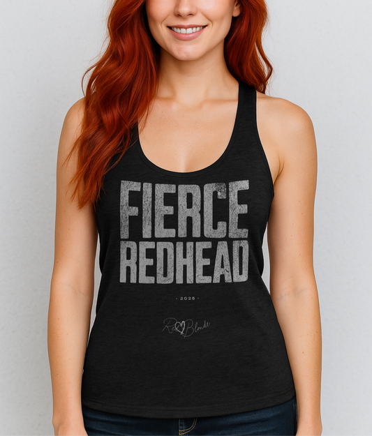 Redhead woman wears black women’s racerback tank top with the bold, distressed North Road font text "FIERCE REDHEAD" in large uppercase white letters across the chest. Below it, in smaller white text, is “• 2025 •” followed by a script-style signature reading “RedBlonde.”