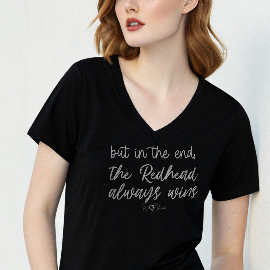 Redhead woman wears black women's v-neck relaxed fit t-shirt featuring the handwritten-style slogan “but in the end, the Redhead always wins” in Hillbear font in black text across the chest, signed off RedBlonde. Branded “RedBlonde London on inside the collar and on the right sleeve