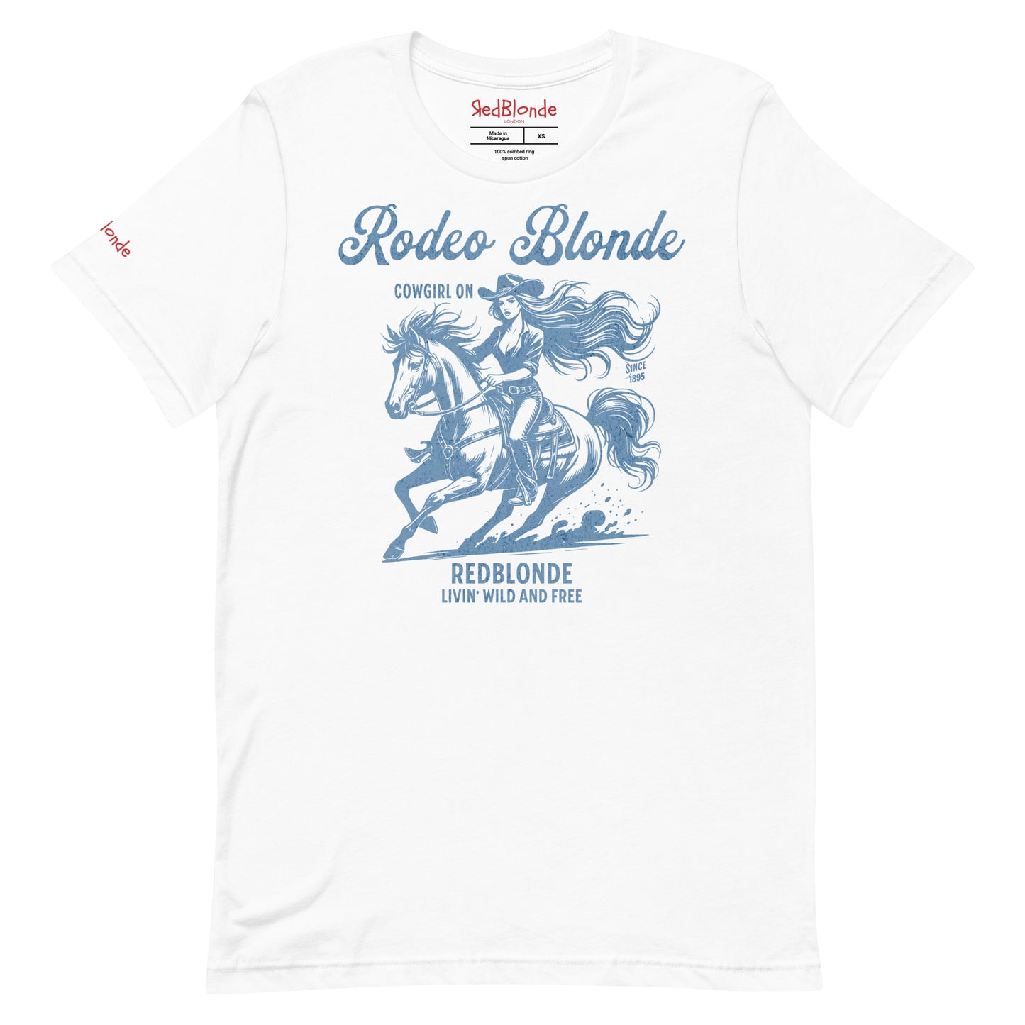 White unisex t-shirt featuring a vintage-style western graphic in soft blue. The design shows a long-haired cowgirl in motion riding a galloping horse, wearing a wide-brimmed hat. Above the image, the text reads "Rodeo Blonde" and "Cowgirl On," while below it says "REDBLONDE – Livin' Wild and Free." RedBlonde branding appears on the inner neck label and right sleeve in red text.