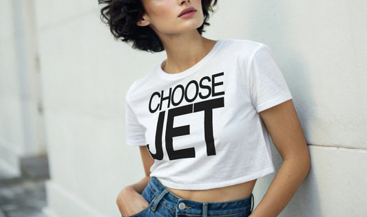 Woman with black hair wears a white women's crop top graphic t-shirt with “CHOOSE JET” in white Helvetica Now font emblazoned on the front.