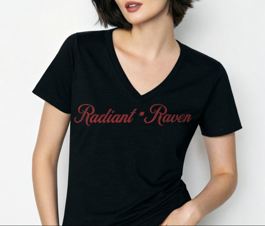 Woman with black hair wears black women's relaxed fit v-neck slogan t-shirt with 'Radiant Raven' in milkshake script red font. Branded RedBlonde in red on inside neck and right sleeve