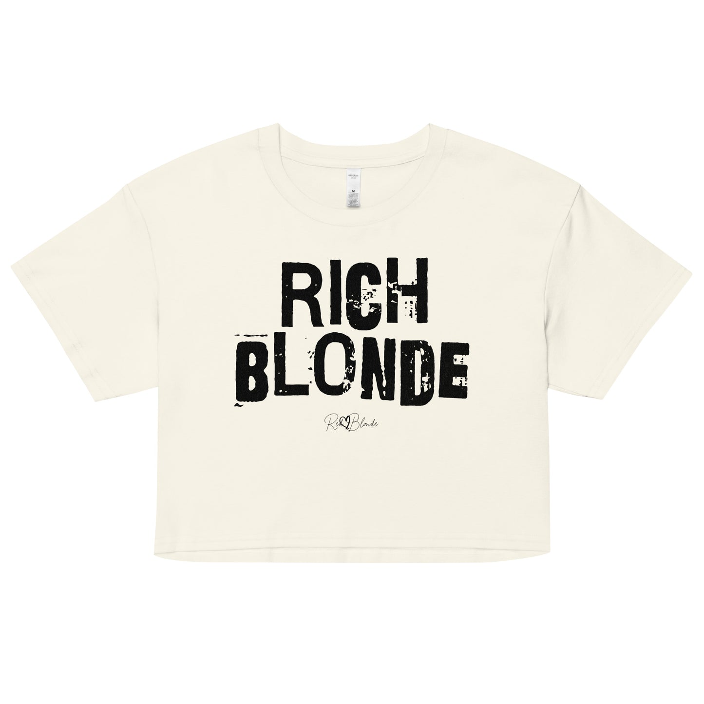 a natural coloured crop top with a relaxed fit, short sleeves, and a wide crew neckline. The front features bold black distressed lettering reading “RICH BLONDE” with the RedBlonde signature logo underneath in white.