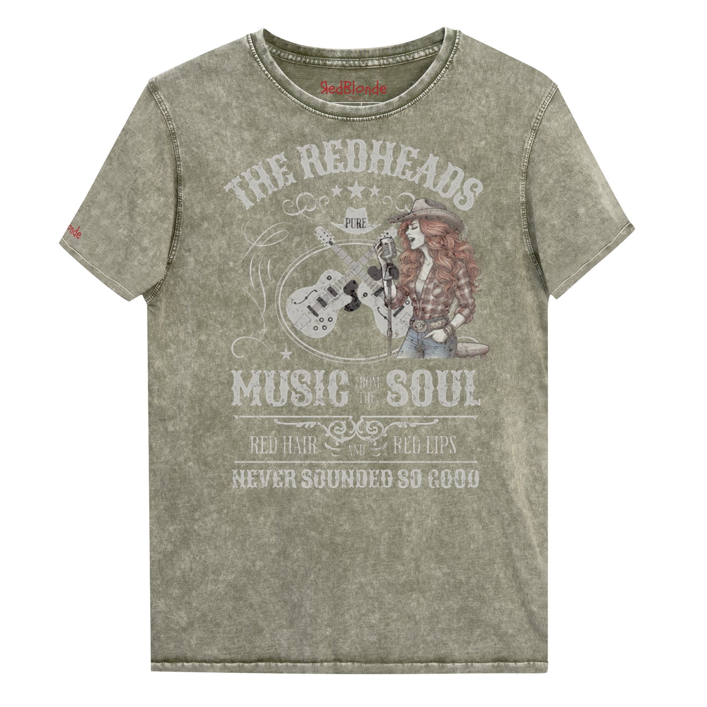 An army green denim wash unisex t-shirt with ‘THE REDHEADS’, ‘MUSIC FROM THE SOUL’, ‘RED HAIR AND RED LIPS’, and ‘NEVER SOUNDED SO GOOD’ written in Sancreek font features a graphic of a redheaded cowgirl singing with two guitars behind her. Branded RedBlonde London in red on inside neck and right sleeve
