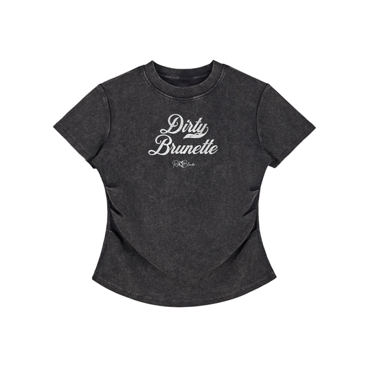 A fitted, short-sleeve black crewneck T-shirt laid flat on a white background. It has subtle ruching/contouring at the sides and a slightly curved hem. White script text across the chest reads “Dirty Brunette,” in Milkstore 01 script with a small cursive “RedBlonde” logo beneath.