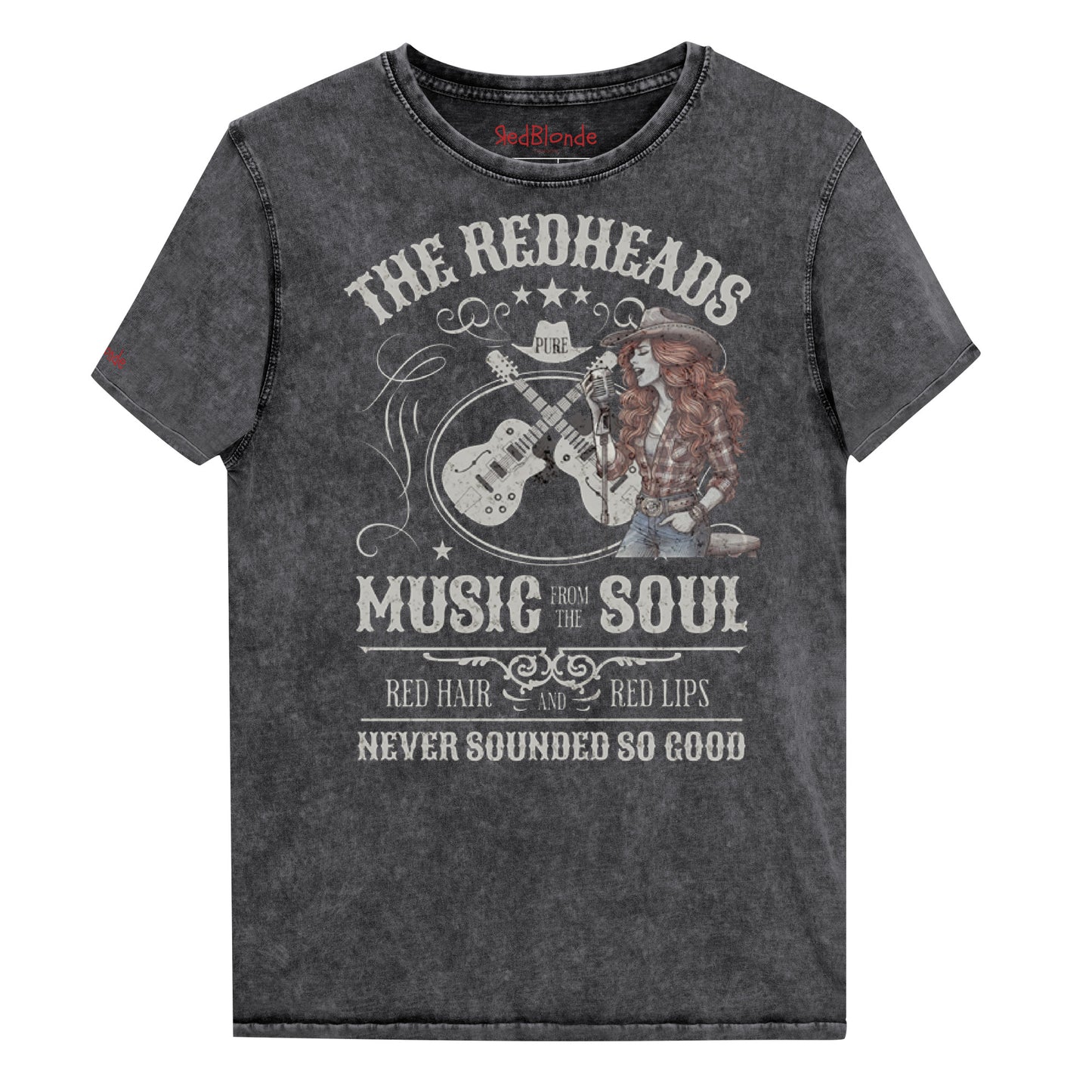 A black denim wash unisex t-shirt with ‘THE REDHEADS’, ‘MUSIC FROM THE SOUL’, ‘RED HAIR AND RED LIPS’, and ‘NEVER SOUNDED SO GOOD’ written in Sancreek font features a graphic of a redheaded cowgirl singing with two guitars behind her. Branded RedBlonde London in red on inside neck and right sleeve