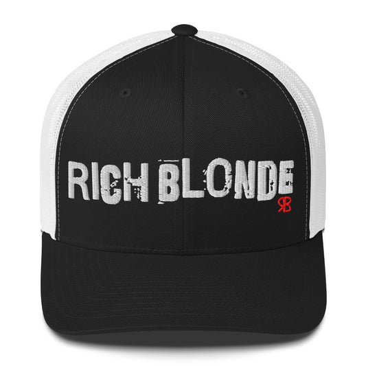 Black and white mesh-back trucker cap with the bold distressed text “RICH BLONDE” embroidered in white across the front, and a small red “RB” logo detail beneath the text. The cap has a structured front panel and curved brim