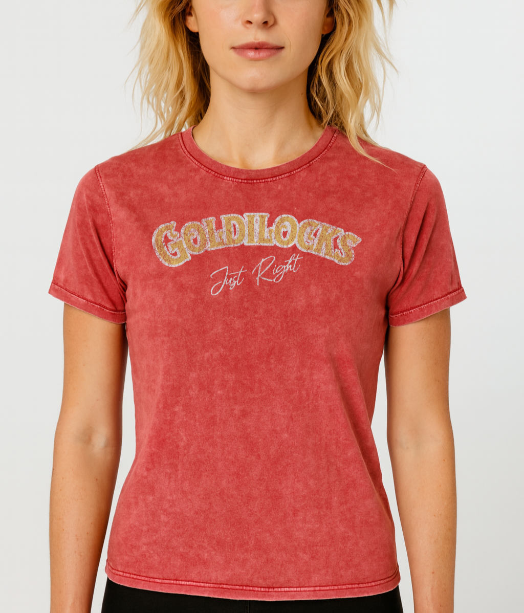 blonde wears Red vintage acid wash look unisex t-shirt with the text “Goldilocks Just Right” in gold and white Signmaster Pro textured font, designed in a bold retro style. Branded RedBlonde on inside neck and right sleeve