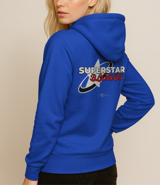 Blonde wears a A Royal Blue unisex pullover hoodie with a large back graphic design. The print features a bold white star with a swoosh around it and the words “SUPERSTAR BLONDE” in white and red retro-style Monsierrat and Molle lettering. The design also includes a small signature logo “R & B Blonde” underneath. Branded RedBlonde on inside neck and right sleeve