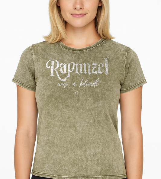 Blonde wears an army green unisex acid denim wash tshirt featuring white fairytale spiky text that reads “Rapunzel" and the phrase “was a blonde” written underneath in an elegant cursive script. signed off with the RedBlonde heart signature logo. Branded RedBlonde on inside neck and right sleeve
