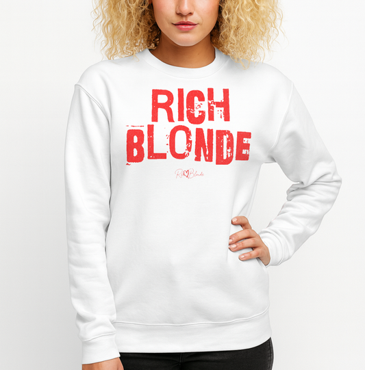 blonde wears a white unisex premium sweatshirt with bold distressed red Ed Geinitext “RICH BLONDE” on the front, featuring a subtle RedBlonde logo beneath the lettering and on the sleeve cuff and inside neck