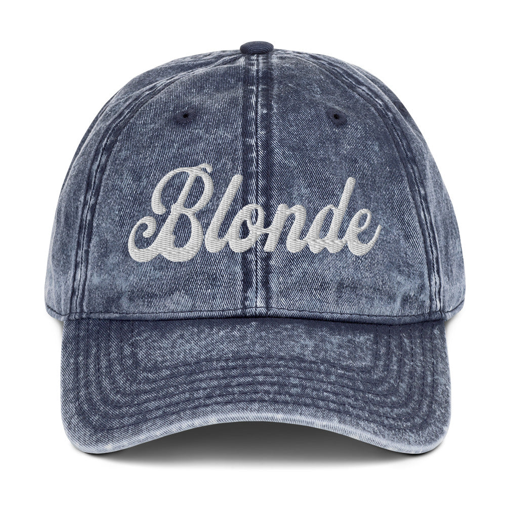 flatlay of blue denim vintage wash effect baseball cap with the word 'Blonde' embroidered on the front in white adventure font