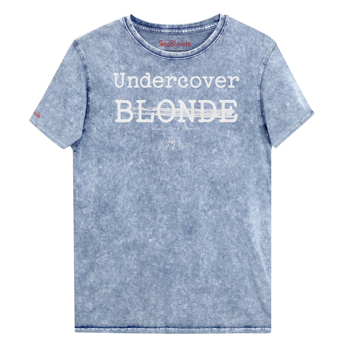 A blue unisex denim-style t-shirt with a vintage washed finish. The front features bold white text reading “Undercover BLONDE” with “BLONDE” partially struck through by a horizontal white bar. Beneath it, smaller text says “mission file // redacted” along with a subtle RedBlonde logo. The shirt has a classic crew neck and short sleeves with visible stitching for a rugged look. Branded RedBlonde London in red on inside neck and right sleeve