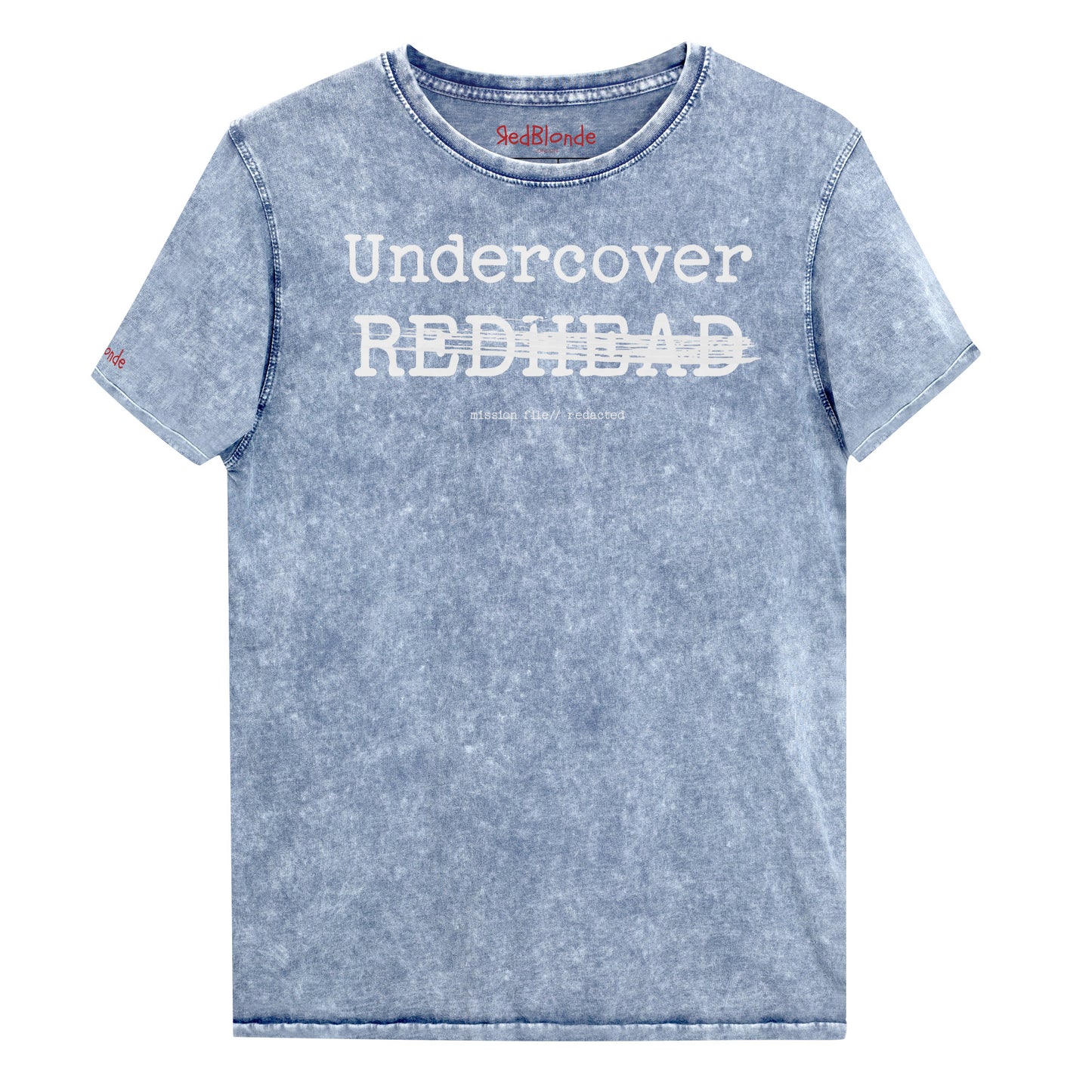 An blue unisex denim-style t-shirt with a vintage washed finish. The front features bold white text reading “Undercover REDHEAD” partially struck through by a horizontal white bar. Beneath it, smaller text says “mission file // redacted” along with a subtle RedBlonde logo. The shirt has a classic crew neck and short sleeves with visible stitching for a rugged look. Branded RedBlonde London in red on inside neck and right sleeve