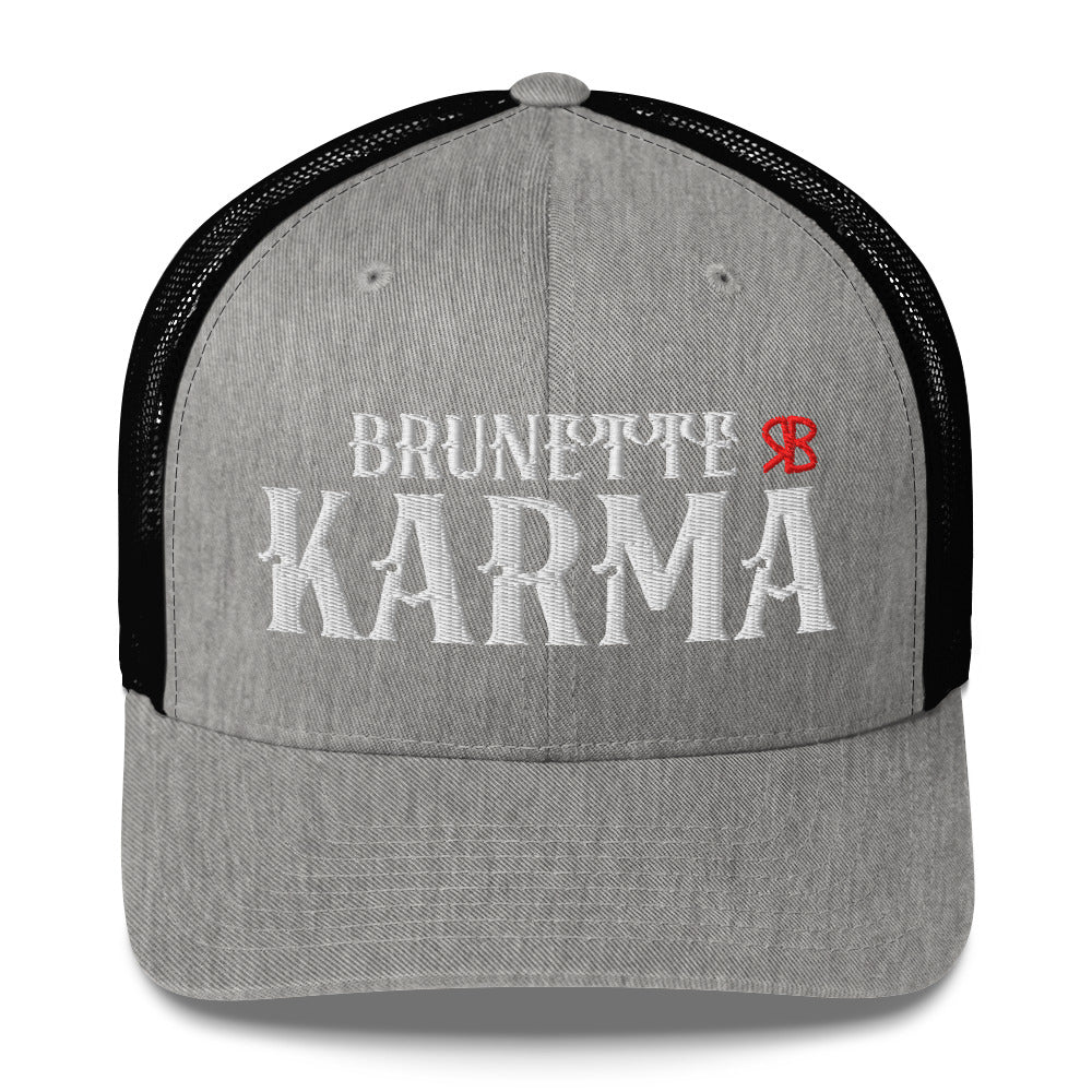 grey/black retro trucker cap with mesh back. The front features bold white embroidered text reading "BRUNETTE KARMA" with a small red RB logo to the right.
