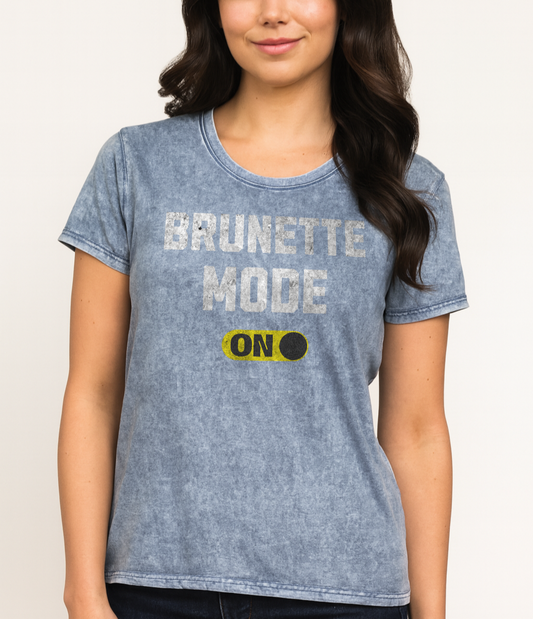 Brunette wears blue denim-style unisex t-shirt with bold distressed white Univercity font reading “Brunette Mode” and a yellow on/off switch graphic in the “On” position beneath. The design includes subtle worn texture for a vintage look. Branded RedBlonde London in red on inside neck and right sleeve
