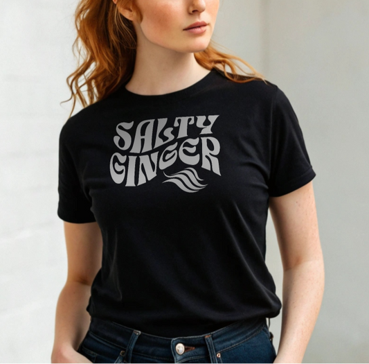 ginger woman wears a black classic unisex graphic t-shirt with the slogan 'Salty Ginger' in Solino Display white retro 70s wavy font. Branded RedBlonde in red on inside neck and right sleeve