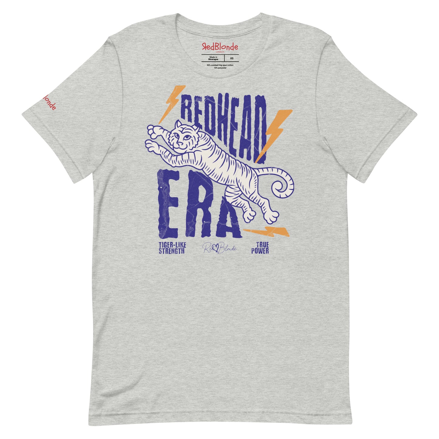 gray unisex short-sleeve t-shirt featuring a bold graphic of a leaping tiger outlined in purple, surrounded by orange lightning bolts. The text “REDHEAD ERA” appears in large distressed purple letters, with smaller text reading “TIGER-LIKE STRENGTH” and “TRUE POWER” underneath. Signed RedBlonde. The brand name “RedBlonde” is printed in red on the inside collar label and on the right sleeve near the cuff.