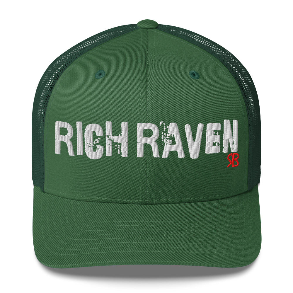 green mesh-back trucker cap with the bold distressed text “RICH RAVEN” embroidered in white across the front, and a small red “RB” logo detail beneath the text. The cap has a structured front panel and curved brim