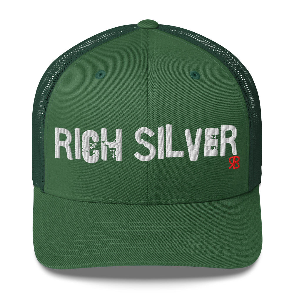 green mesh-back trucker cap with the bold distressed text “RICH SILVER” embroidered in white across the front, and a small red “RB” logo detail beneath the text. The cap has a structured front panel and curved brim