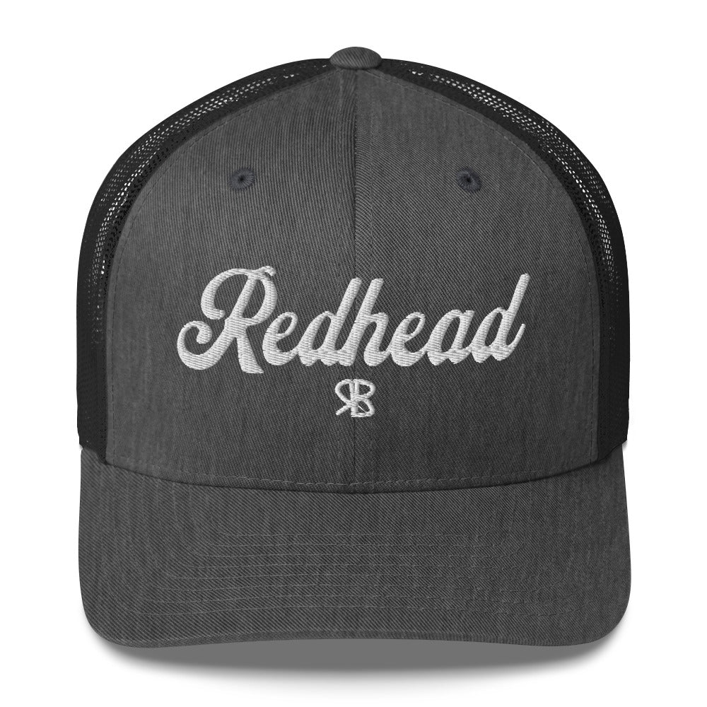 grey/black trucker cap with 'Redhead' in white adventurer 01 font on front. Mesh back. Branded RB