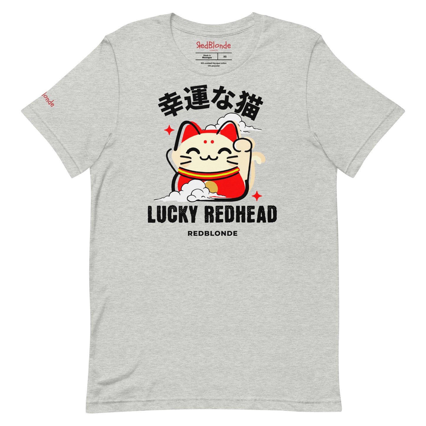 A grey unisex T-shirt featuring a colorful maneki-neko (lucky cat) graphic wearing a red outfit with gold accents. Above the cat, Japanese kanji characters are printed in bold white. Below the illustration, the text reads “LUCKY REDHEAD” in distressed white font, with “REDBLONDE” in smaller uppercase letters underneath. The shirt has short sleeves, a classic crew neckline, and a casual, modern fit.