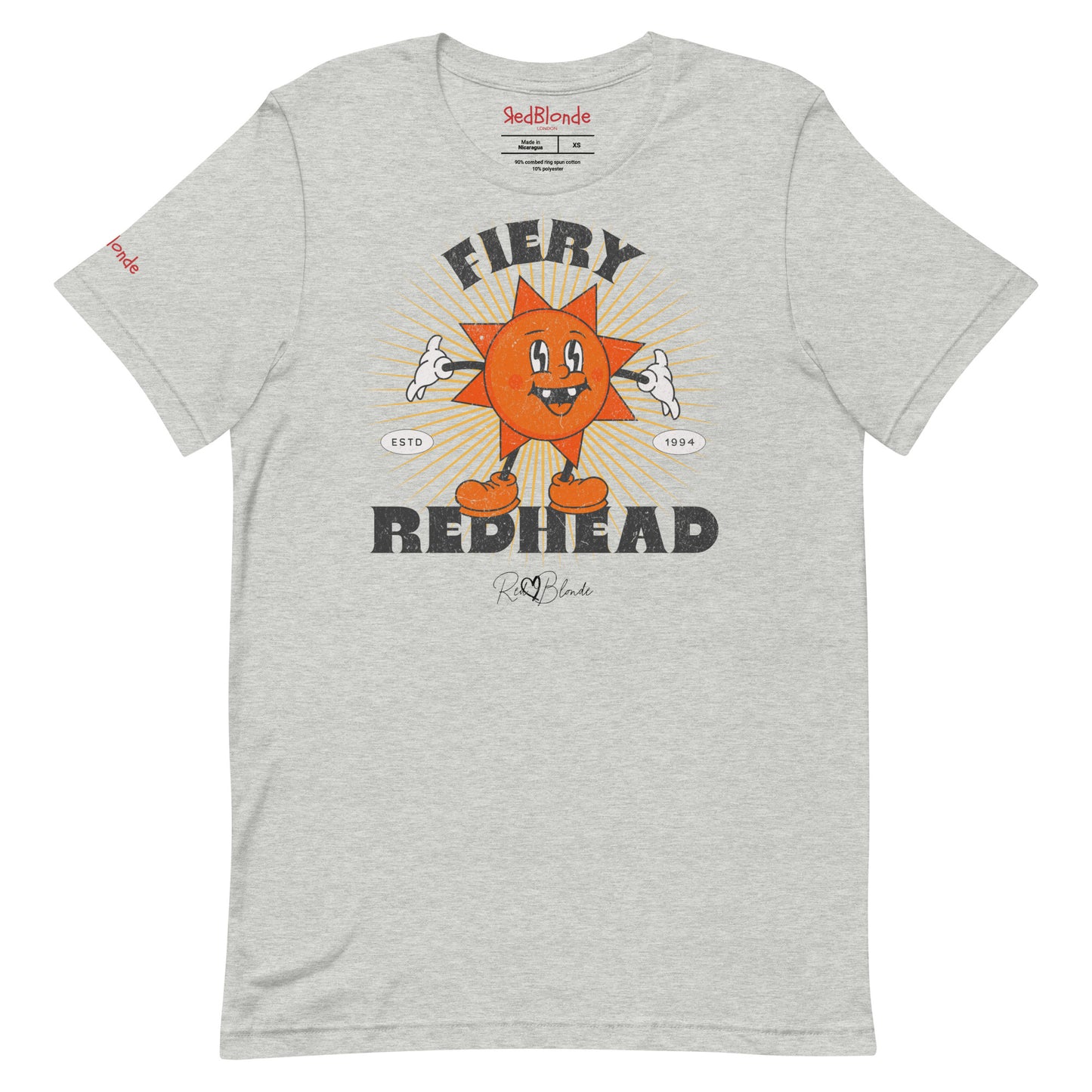 Heather grey unisex crew neck t-shirt with a bold retro graphic of a smiling orange cartoon sun character, surrounded by radiant sunbeams. The text reads ‘Fiery Redhead’ in distressed black Belzebuth lettering with small details including ‘ESTD 1994’ and the RedBlonde signature logo beneath."