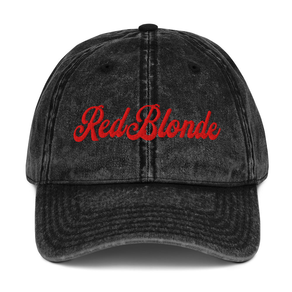 flatlay of vintage black denim wash effect baseball cap with the word 'RedBlonde' embroidered on the front in white adventure type script font
