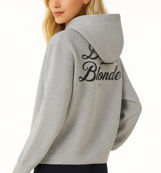 Back view of a model wearing a grey hoodie with bold white Milkstore vintage-style script text “Dirty Blonde” across the back and a subtle RedBlonde signature logo underneath.
